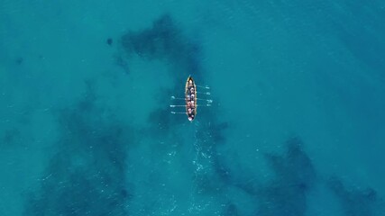 A rowing boat on beautiful blue water. Top down aerial shot.