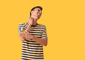 Young man scratching himself on color background