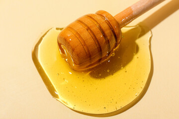 Wooden dipper with sweet honey on color background, closeup