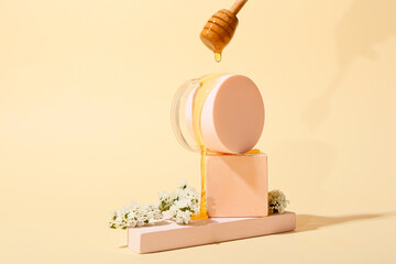 Pouring of sweet honey onto jar of cosmetic product on color background