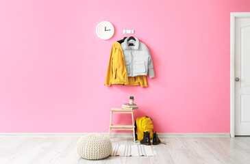 Interior of hallway with stylish jackets and pink wall