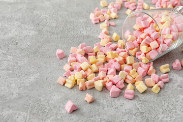Glass with tasty marshmallows on grey background
