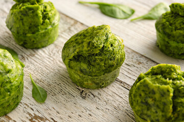 Tasty spinach muffins on light wooden background, closeup