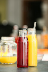 Bottles with healthy juice on table in room