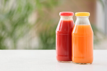 Bottles with healthy juice on table in room, closeup