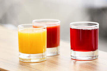Glasses with healthy juice on table in room, closeup