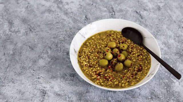 vegan spicy barley with olives and chilli flkes topping, healthy plant-based food