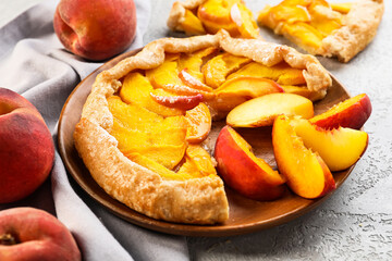 Plate with tasty peach galette on light background, closeup