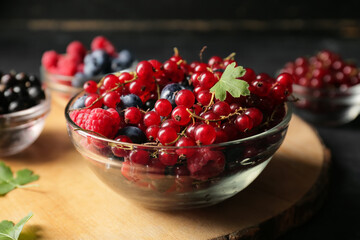 Bowl with ripe berries on wooden table, closeup