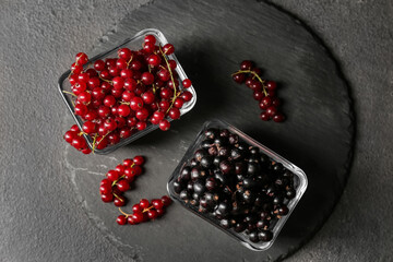 Bowls with ripe red and black currant on dark background