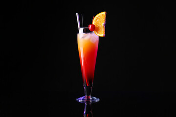 Glass of tasty Tequila Sunrise cocktail on dark background