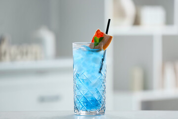 Glass of Blue Lagoon cocktail on table in room