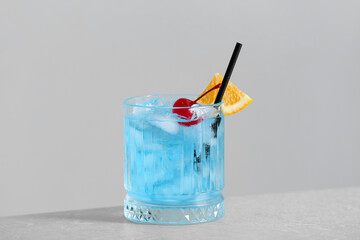 Glass of Blue Lagoon cocktail on table against light wall