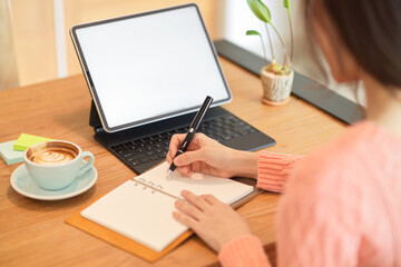 Female business owner, college student, businesswoman working on tablet while writing on her book.