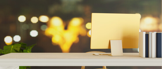 Copy space on modern computer desk with yellow computer over blurred bokeh light in the background.