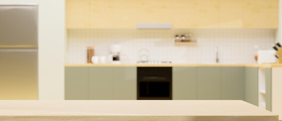 Modern light wooden kitchen counter island over blurred modern green and wooden kitchen interior.
