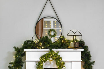 Fireplace with garland, wreath and mirror near light wall