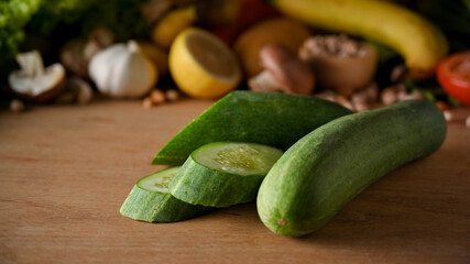 Fresh cucumber and cucumber slides on wooden table
