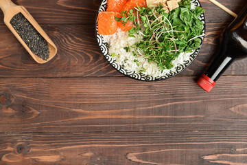 Tasty poke bowl with sauce on wooden background