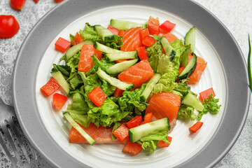 Tasty salad with salmon and vegetables in plate on table, closeup