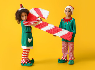 Cute little elves with candy cane pinata on yellow background