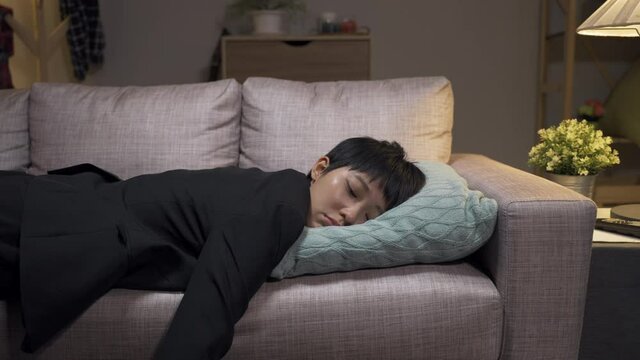 slow motion of tired asian female employee off work, and diving into the couch and falling asleep in the living room after going back home.