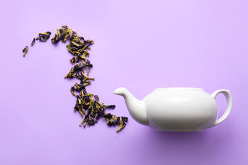 Creative composition with teapot and dried butterfly pea flower tea on color background