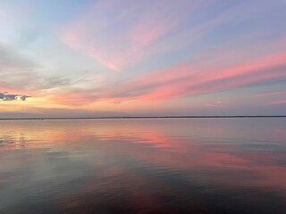 Naklejka premium pastel sunset with reflections over calm bay water 