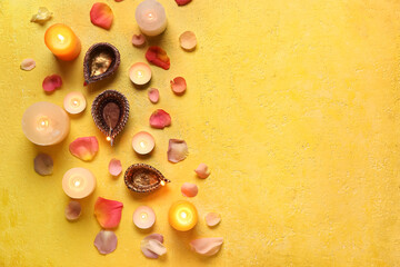Diya lamps for Diwali, candles and flower petals on color background, top view