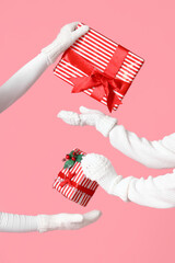 Women exchanging Christmas gifts on pink background