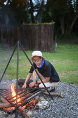Young man traveler make bonfire  near camping tents in forest.