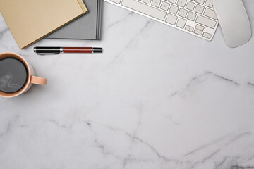 Top view woman workspace with cup of coffee, notebooks and keyboard on marble table.