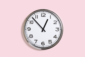 Big plain wall clock on pastel pink background. One o'clock. banner with copy space, time...