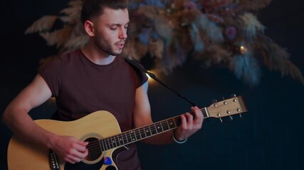 Male musician playing acoustic guitar. Guitarist plays classical guitar on stage in concert Handsome young hipster male guitar player perform private party Stylish long hair Medium shoot
