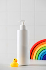 Dispenser bottle of baby cosmetic product with place for text and duck on table