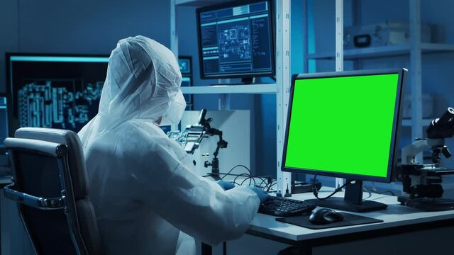 Scientist works in a modern scientific laboratory for the research and development of microelectronics and processors. Microprocessor manufacturing worker uses computer with chroma key green screen.