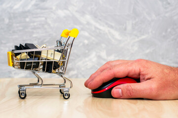 shopping cart with keyboard buttons and a hand with a computer mouse online business concept