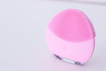 Modern beauty gadgetn white vkground. Facial massager and cleanser device.Copy space