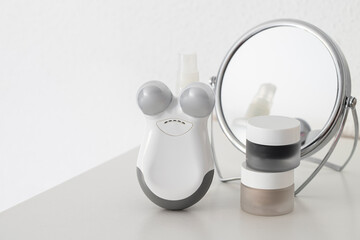 Microcurrent facial tonig device and cleansing and hydrating mask on white table with mirror  Modern beauty care concept