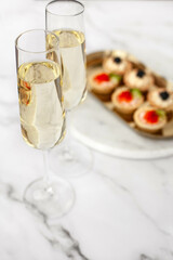 canape with black caviar and soured cream near glass with champagne