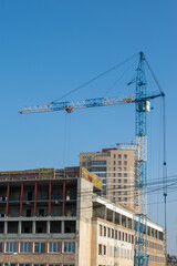 Blue construction crane and building under construction on blue sky background