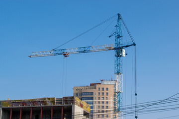 Building under construction on blue sky background. Blue construction crane