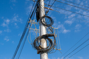 Blue sky background with coils of electrical wires on a street pole against
