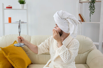 Handsome man cleaning face skin with batting cotton pads and looking at mirror. Spa, body and skin care for male concept.