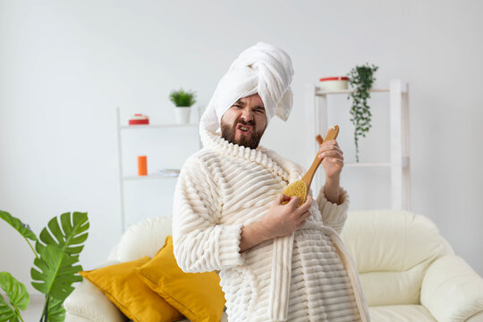 Funny handsome man pretends to play on massage brush as a guitar. Fun, spa and humor concept.