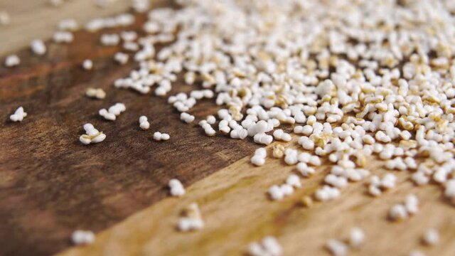 Amaranth popped, puffed grains on a rustic wooden surface. Pseudocereal food, gluten free. Macro. Dolly shot