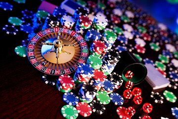 
Casino theme.  Roulette wheel and poker chips on  colorful bokeh background.
