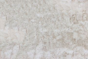 Shabby wall of an old house with uneven crumbling plaster. Yellow-gray abstract texture.