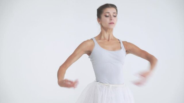 Elegant female in a white tutu, dance ballet and perform choreographic elements on a white background, rehearsal.