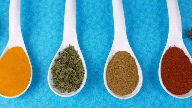 Pan shot of turmeric powder  fenugreek leaves  and cumin powder - Indian spices. Exotic spices star anise and cinnamon kept together on a blue table mat - cooking ingredients  Indian kitchen  aromatic